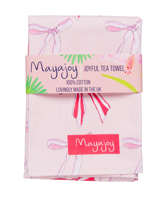pink and red tea towel featuring candy stripe bows with coral belly band saying  'joyful tea towel, 100% cotton, lovingly made in the UK'.
