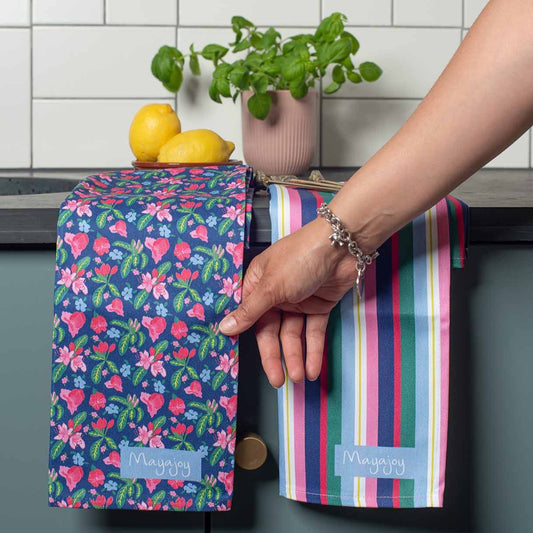 Colourful Striped tea towel in navy blue, pink and green hanging on edge of kitchen cabinet