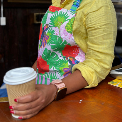 Colourful cotton kitchen apron with hand illustrated hummingbird print in pinks, green, blue and red.