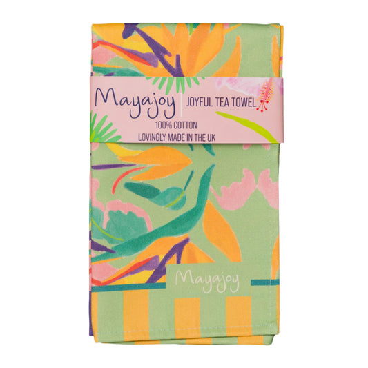 Mayajoy colourful cotton tea towel in paradise design, featuring orange bird of paradise flower with pink, green and purple, folded with coral belly band and words “joyful tea towel”.