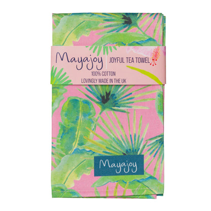 Colourful cotton tea towel in hand illustrated pink palm design with green, blue and pink foliage, folded with coral belly band and words “joyful tea towel” by Mayajoy 