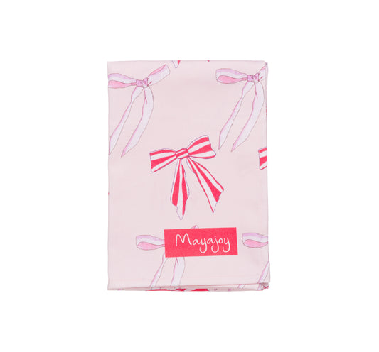 Mayajoy Xmas bows tea towel, in pink and red with nostalgic festive bows and red Mayajoy logo to bottom corner
